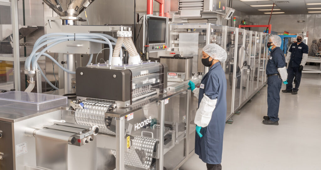 Vitaquest factory with workers operating machines.